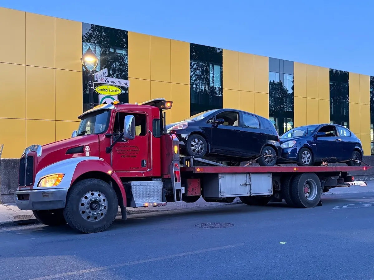 Camion plateau qui ramasse deux autos achetées à Montréal